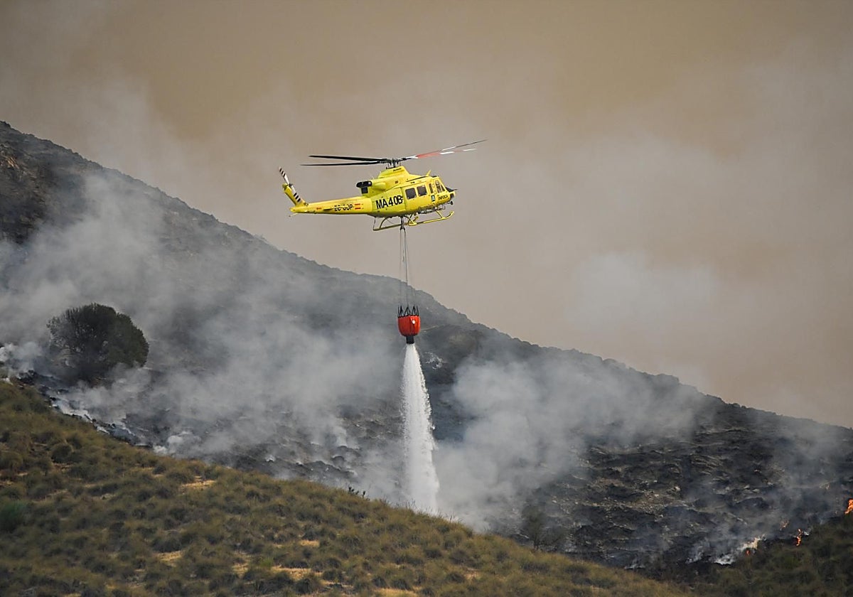Un helicóptero del servicio de extinción de incendios arroja este viernes agua sobre uno de los focos del incendio forestal declarado en Los Gallardos, Almería