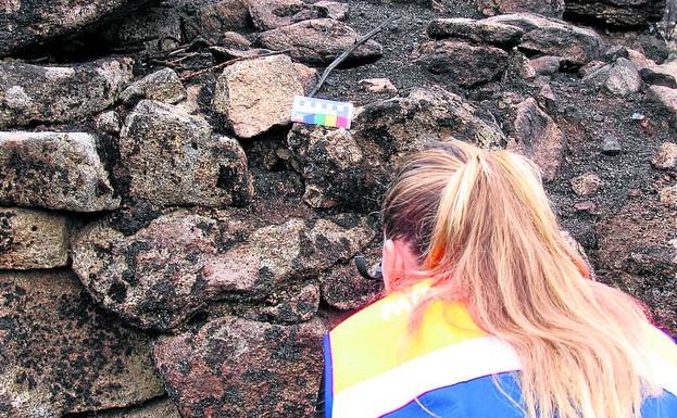 Una técnico de Ugrecyl toma imágenes del muro de la plaza de toros de piedra junto a la ermita de Medinilla, en la provincia de Ávila. 