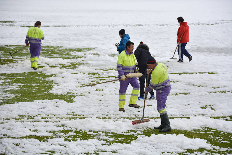 Operarios del servicio de mantenimiento del campo y voluntarios se afanan en retirar la nieve y el hielo del terreno de juego de El Plantío antes del Burgos CF - Barakaldo.