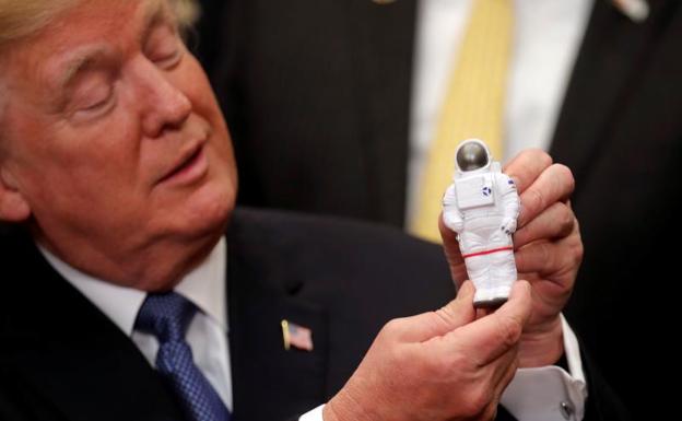 Donald Trump muestra una figura de un astronauta.