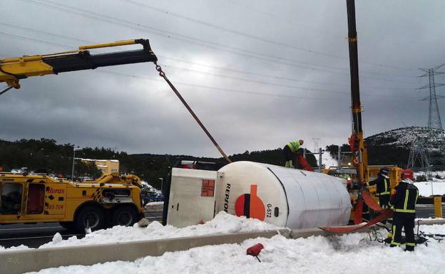 Dos grúas elevan con cuidado el vehículo y la carga ante la supervisión de bomberos de Segovia trasladados al lugar del accidente. 