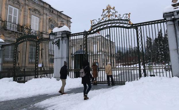 Un grupo de personas observa los jardines a través de la verja de hierro. 