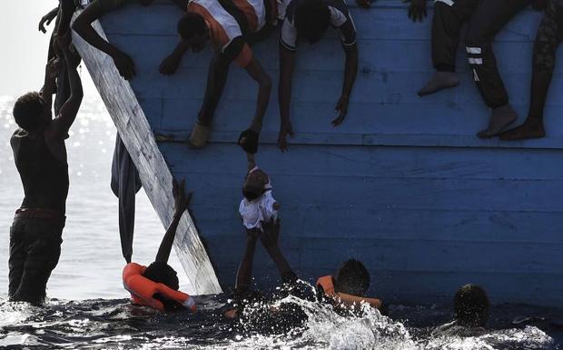 Varios inmigrantes tratan de sacar a los más pequeños del agua.