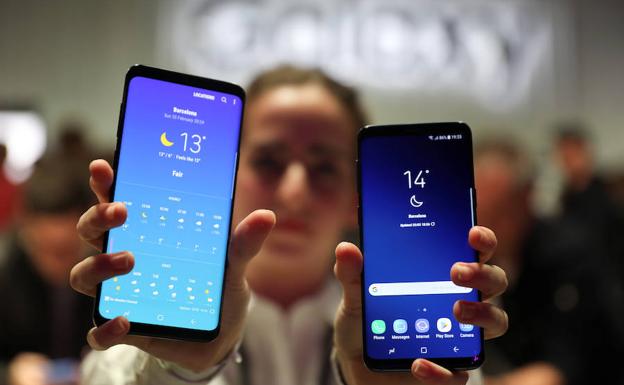 Una mujer muestra dos nuevos modelos de Samsung. 