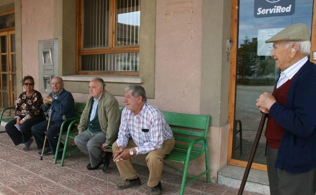 Vecinos del municipio segoviano de Lastras de Cuéllar esperan al autobús de Bankia.