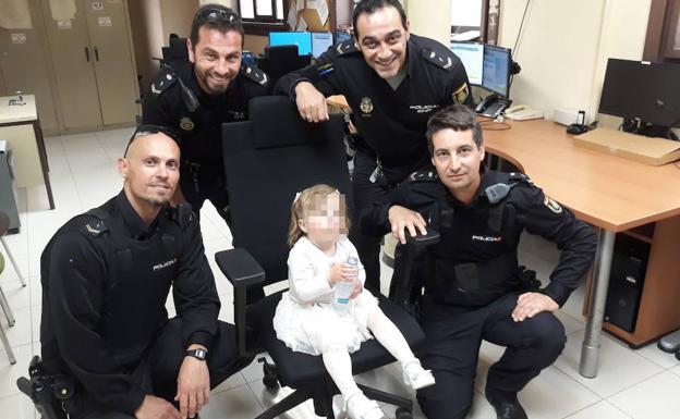 Los policías que localizaron y auxiliaron a la niña, con la pequeña en Comisaría.