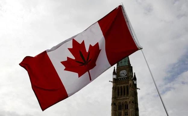 Una bandera canadiense con una hoja de marihuana frente al Parlamento canadiense.