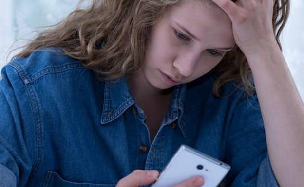 Una chica mira su teléfono móvil.