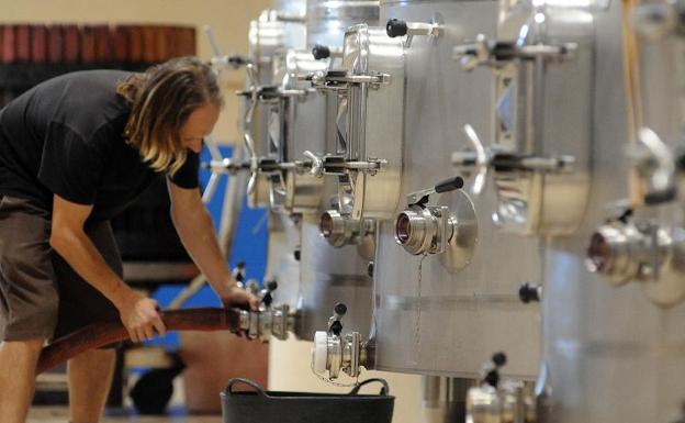 Trabajadores remontando vino en una bodega de León 