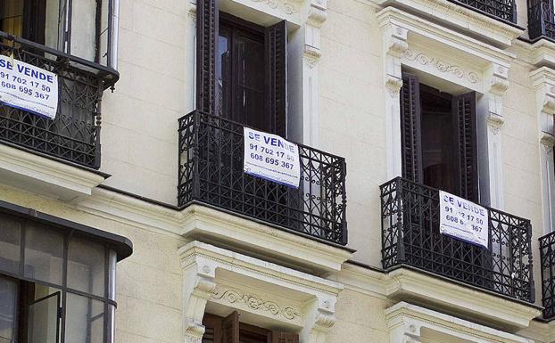Un bloque de apartamentos en Madrid con carteles anunciando su venta.