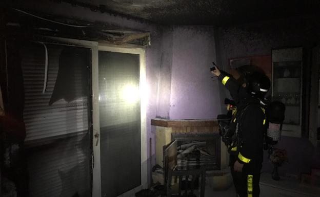 Un bombero inspecciona el salón de la vivienda.