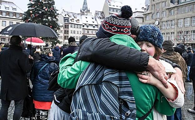 Varias personas se abrazan tras un homenaje a las víctimas de Estrasburgo. 