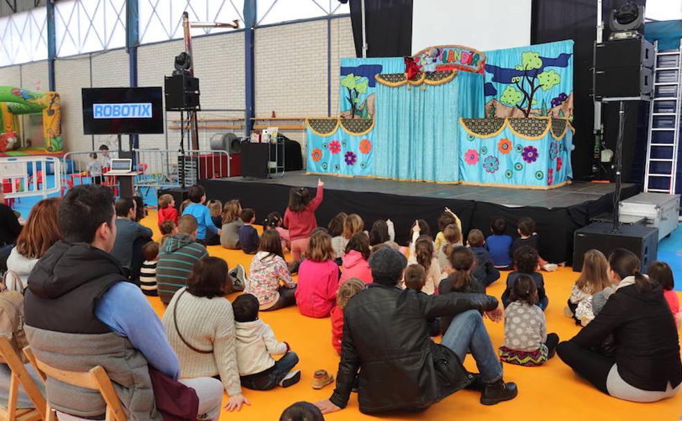 Un grupo de niños, acompañados por familiares, disfrutan de una función de marionetas.