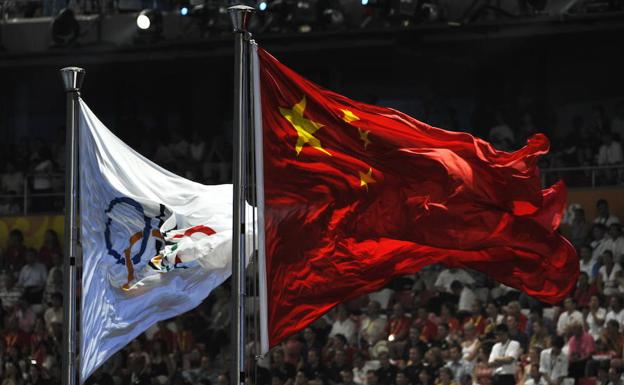La bandera de China ondea junto a la olímpica. 