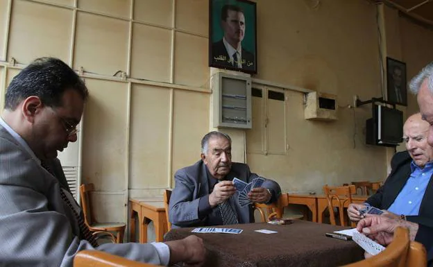 Varios hombres juegan a las cartas en un café de Damasco.