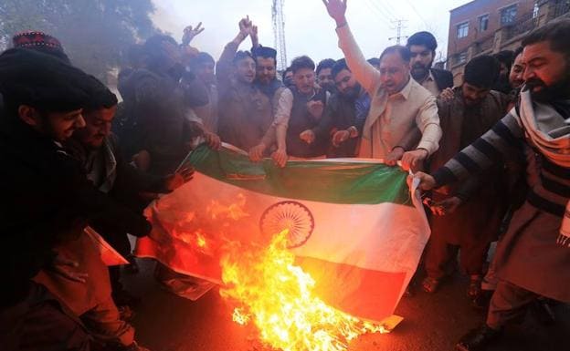 Manifestantes gritan consignas y queman una bandera india durante una protesta tras el bombardeo indio en territorio paquistanú, este martes, en Peshawar, Pakistán. 
