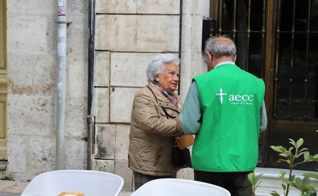 Una mujer echa dinero en las huchas de la AECC Burgos en el día de la cuestación. 