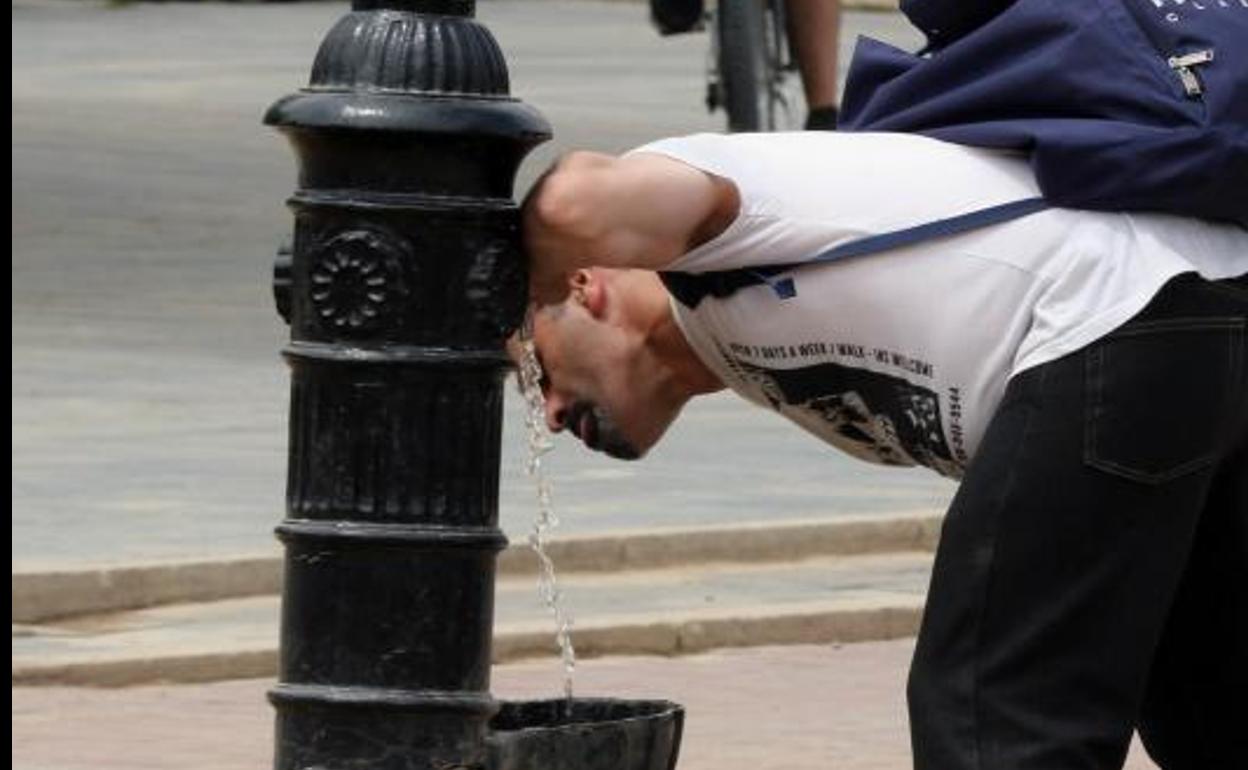 Un hombre se refresca en una fuente de la Playa Moreras de Valladolid.