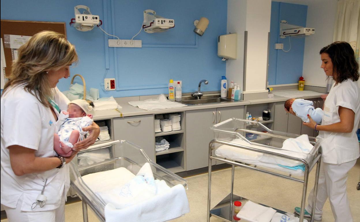 Dos sanitarias llevan entre sus manos a dos recién nacidos.