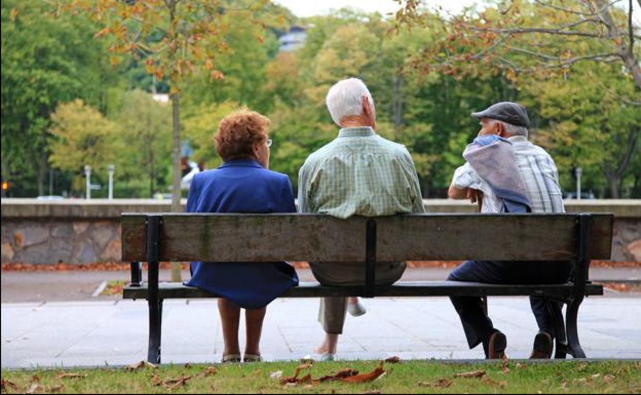 Una mujer y dos hombres sentados en el parque. 