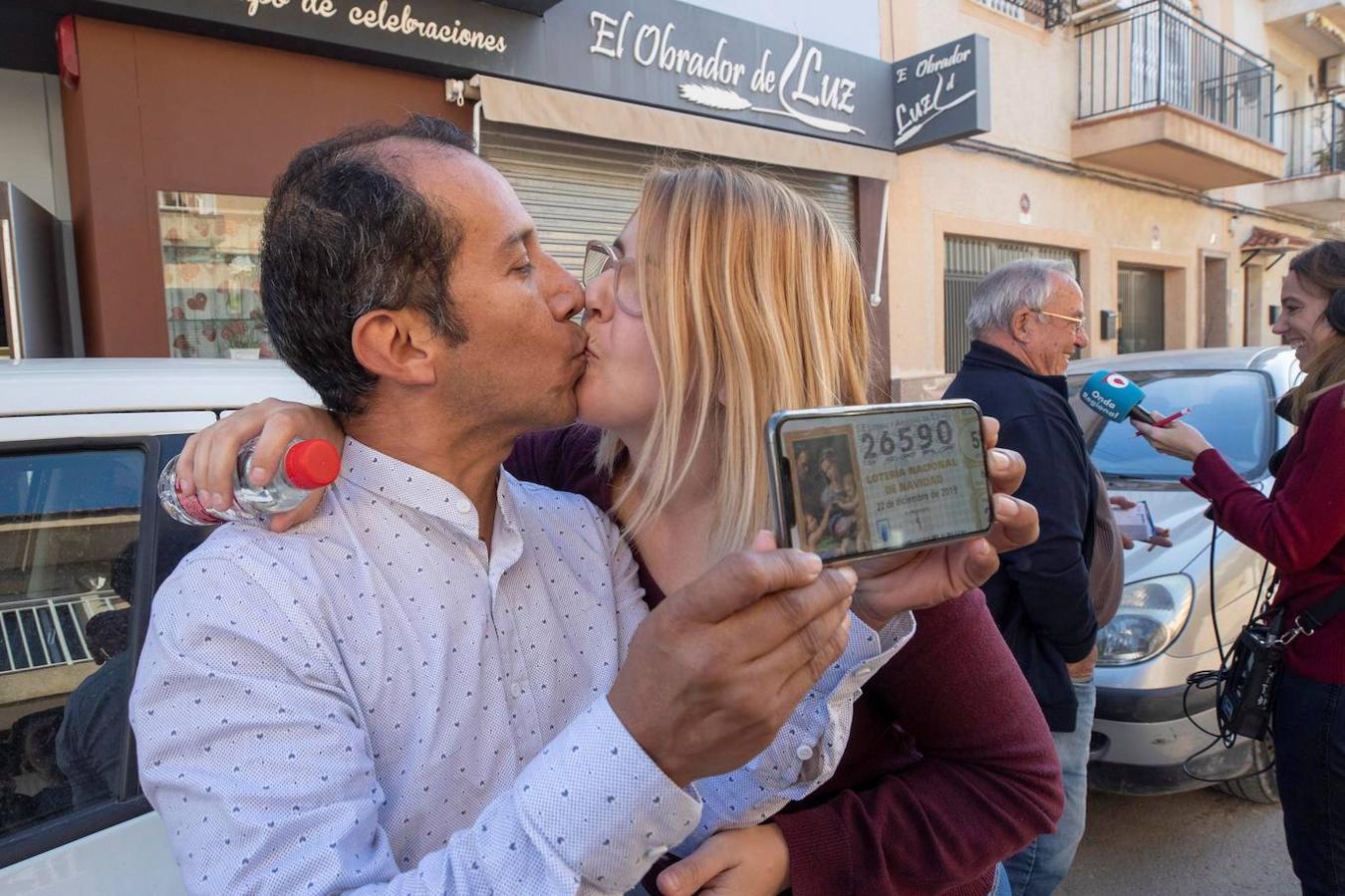 Navidad Yesica Garcia y Alexander Zambrano se besan monstrando el número premiado en su móvil en Las Torres de Cotillas (Murcia).