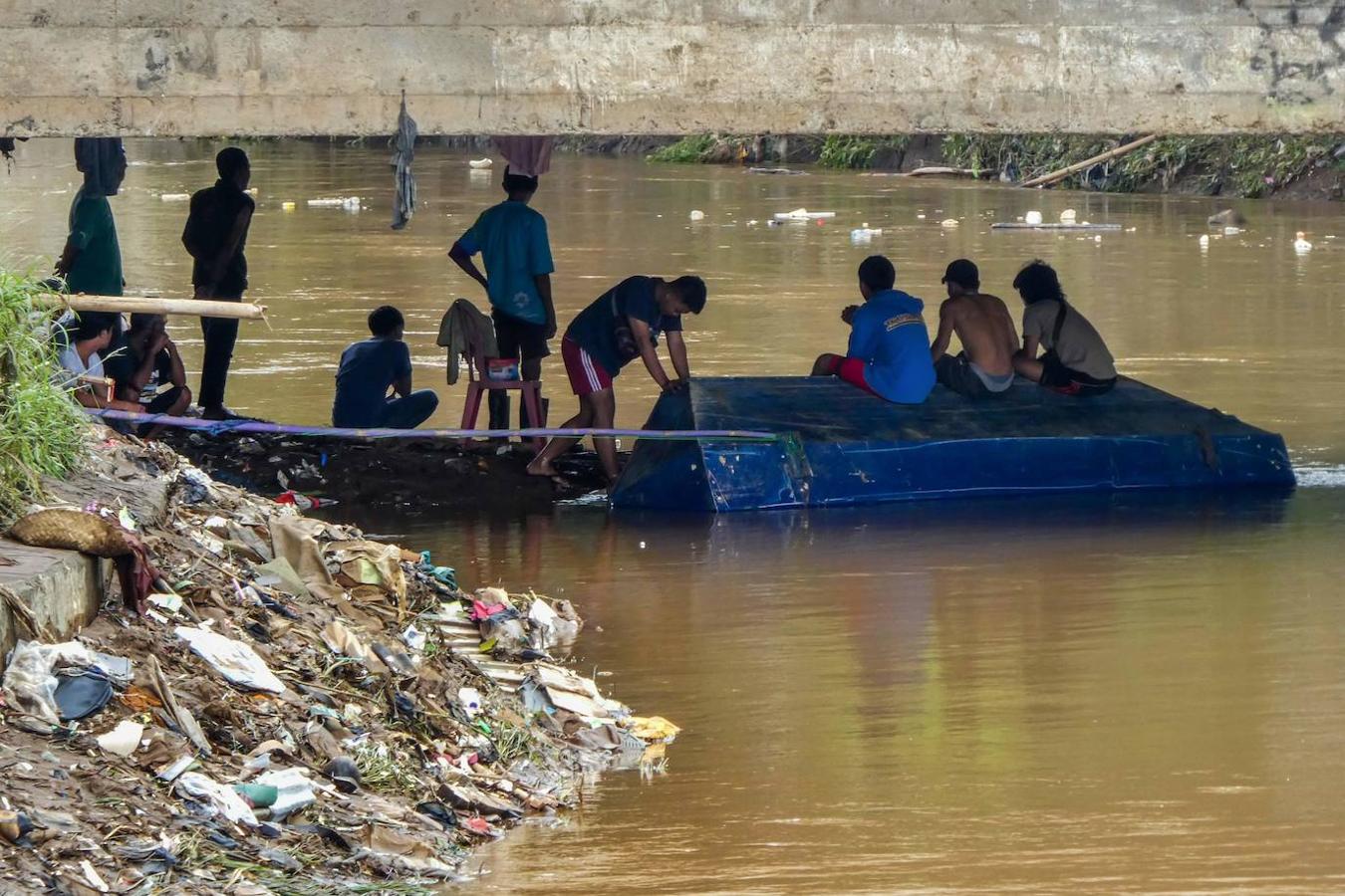 Un grupo de personas se refugia bajo un bloque de hormigón tras las inundaciones de Yakarta, Indonesia.