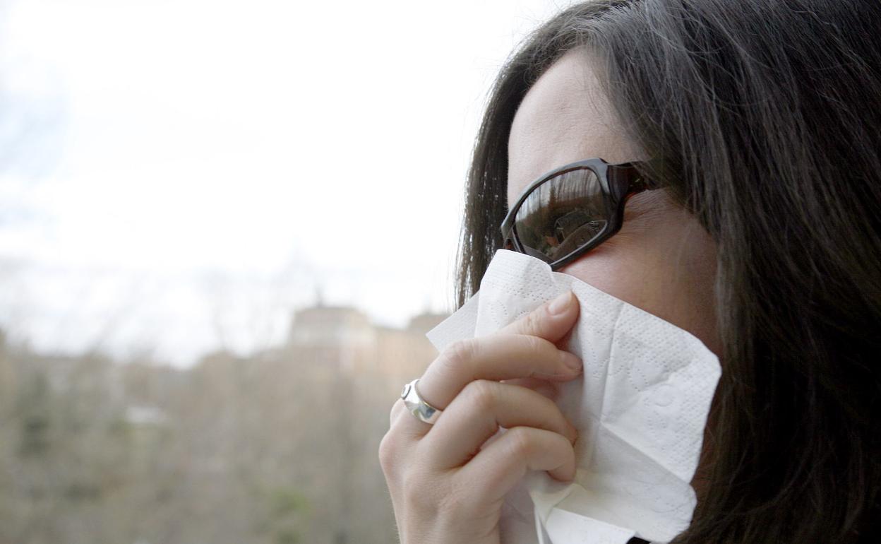 Una mujer estornuda por una alergia. 