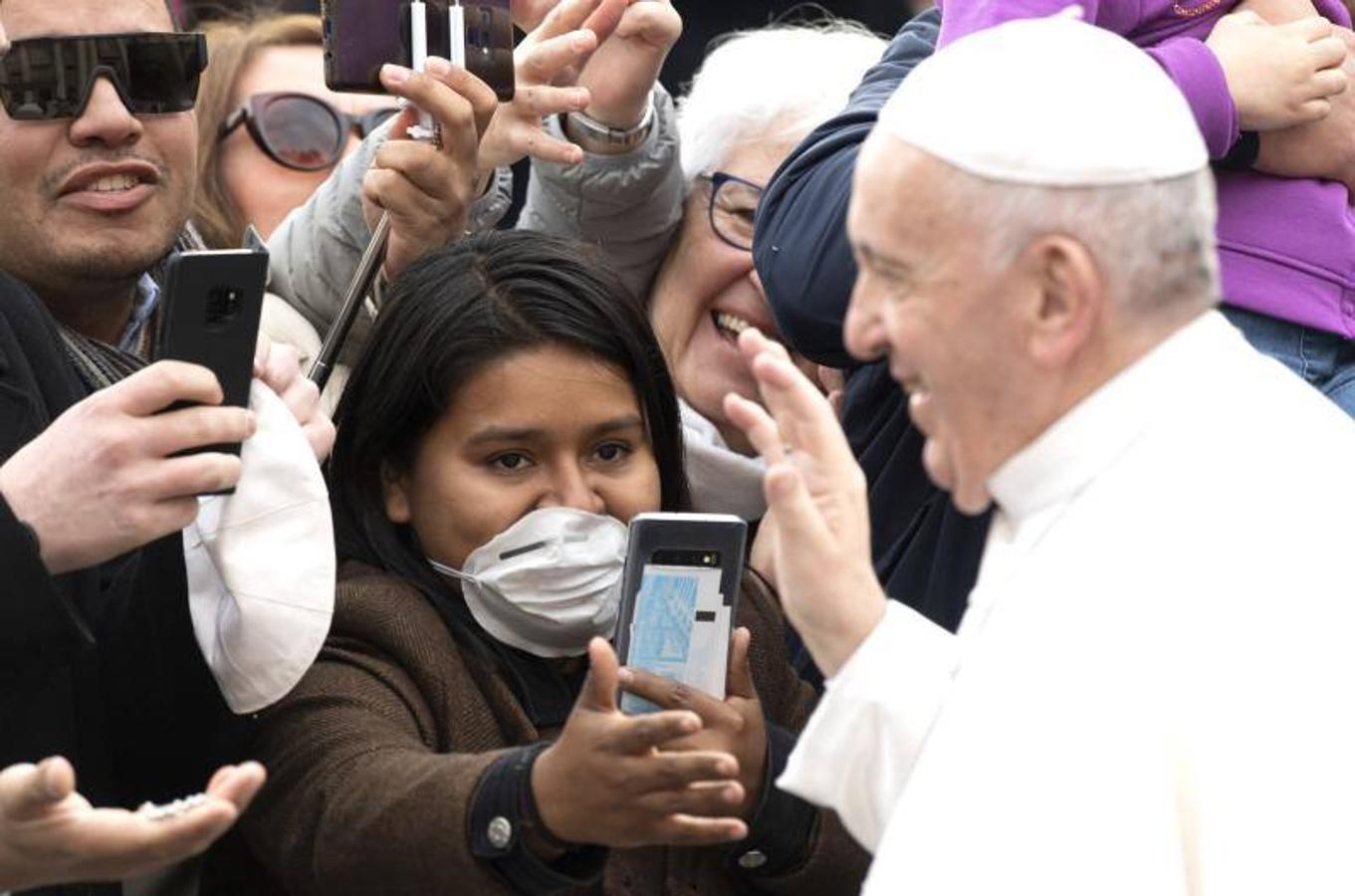 El Papa Francisco saluda a los fieles, muchos de los cuales llevan máscaras médicas debido al brote continuo de coronavirus