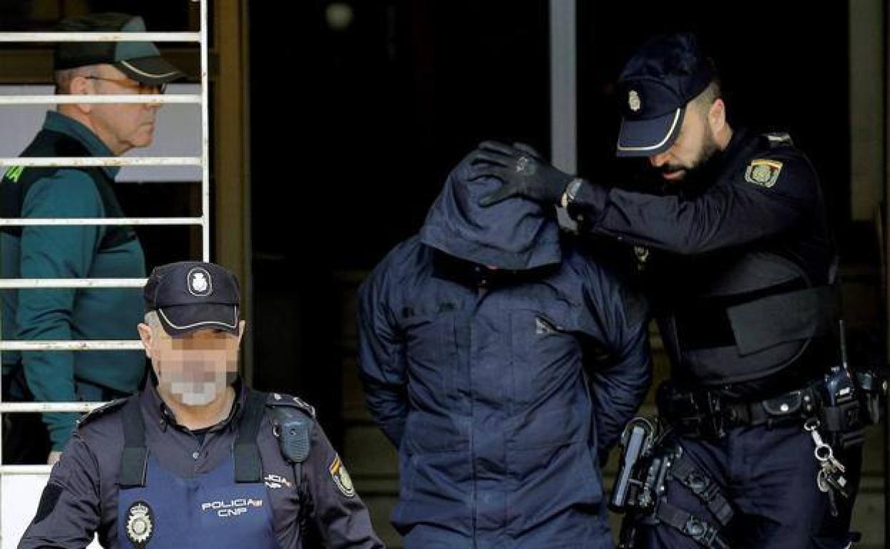 El presunto homicida, custodiado por dos policías. 