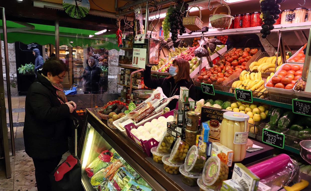 Ana, de Frutería Maestre, despacha a una clienta con la mascarilla y los guantes. 