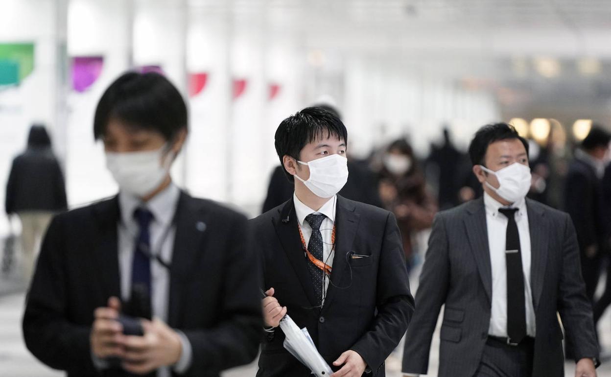 tres hombres con mascarilla en Tokio. 