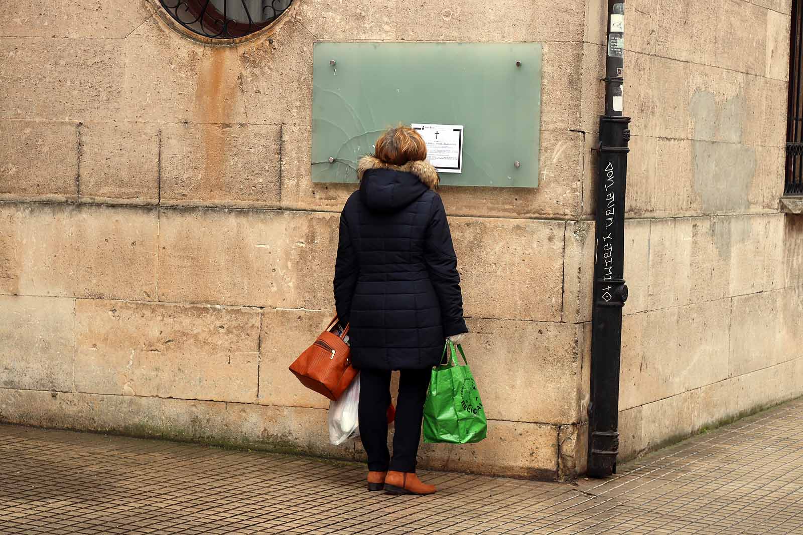 Una vecina consulta una esquela en la calle.