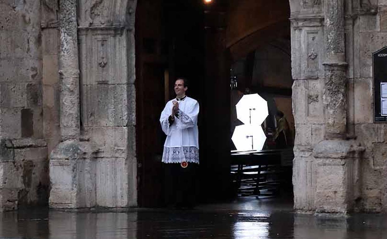 El párroco de San Cosme y San Damián aplaude a los sanitarios en la puerta de su parroquia.