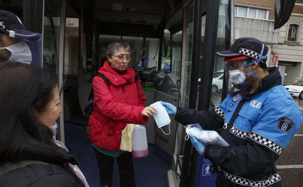 Un policía municipal reparte mascarillas en la puerta del autobús. 