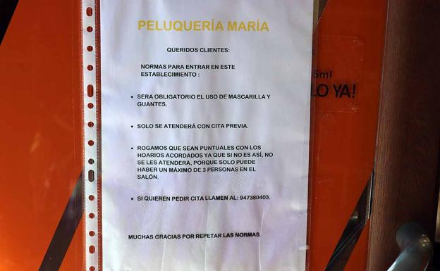 Cartel en la puerta de acceso a una peluquería en Salas de los Infantes en el que se especifican las medidas de seguridad e higiene frente a la covid-19.