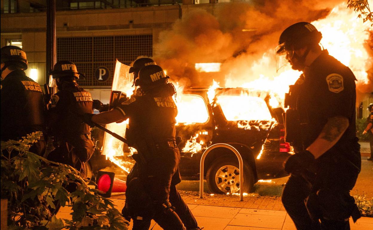 Policías de Washington pasan junto a varios coches incendiados.