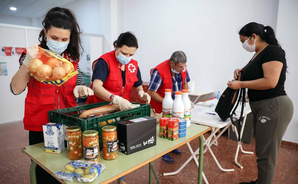 Voluntarios de la Cruz Roja entregan ayudan a personas en riesgo de exclusión, en Valencia.