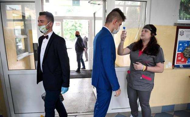 Alumnos polacos de Przemysl, en Polonia, se toman la temperatura antes de su ceremonia de graduación. 