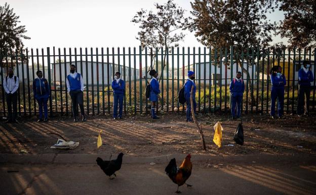 Alumnos de la escuela Winnie Mandela, en Tembisa, Sudáfrica, guardan la distancia de seguridad en la cola. 