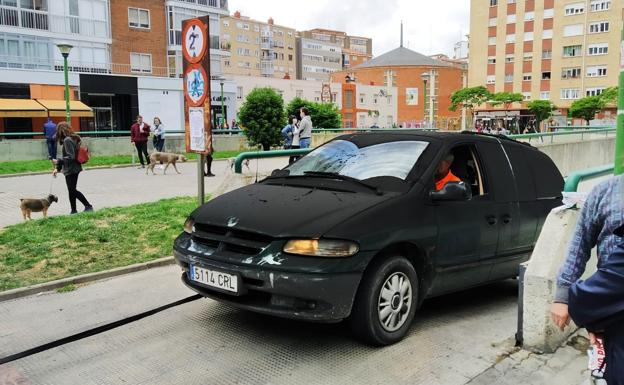 Un vehículo sale remolcado y completamente negro del aparcamiento afectado por el fuego en Gamonal. 