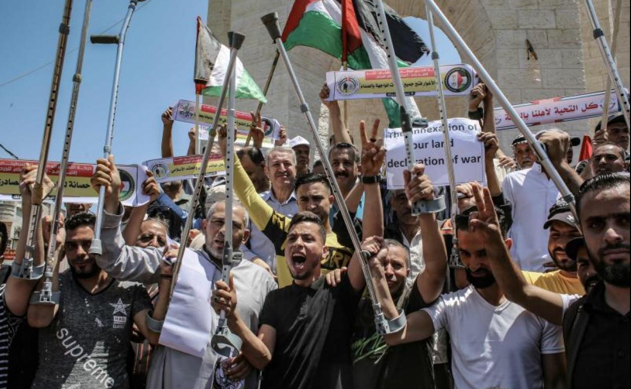 Palestinos mutilados levantan sus muletas durante una protesta en la Franja de Gaza contra los planes de Israel en Cisjordania.