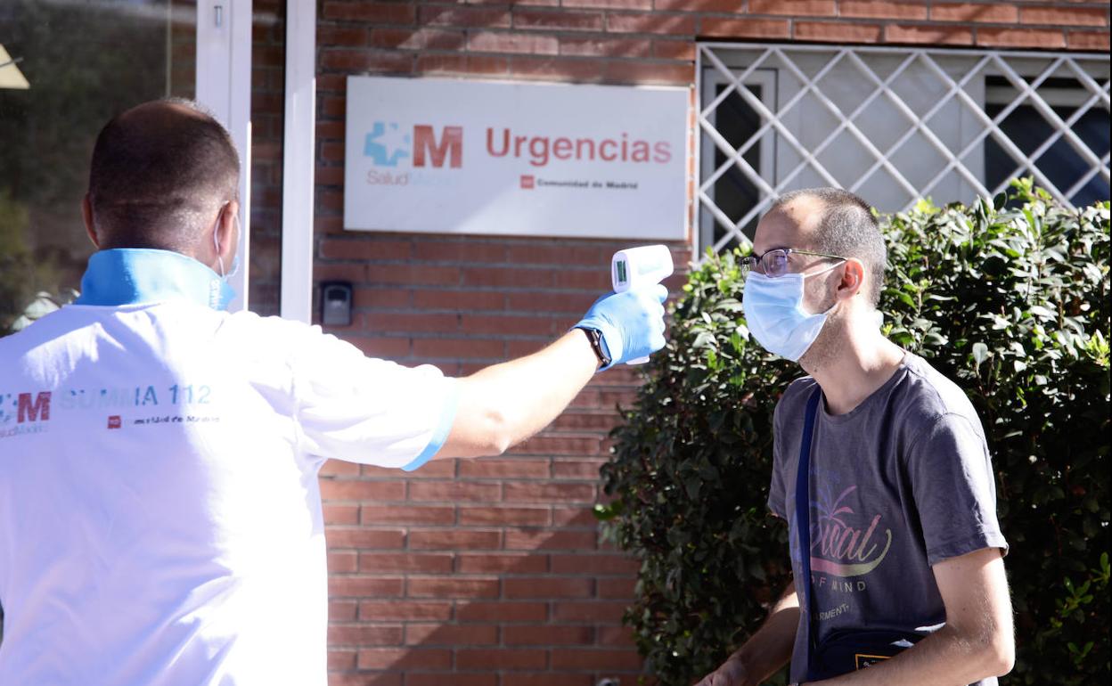 Personal sanitario de la Comunidad de Madrid toma la temperatura a un hombre en un cribado masivo de PCR en la localidad de Alcobendas.