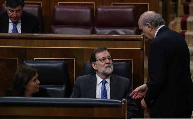 Rajoy charla con su ministro del Interior, Jorge Fernández Díaz, durante un pleno del Congreso en junio de 2017.