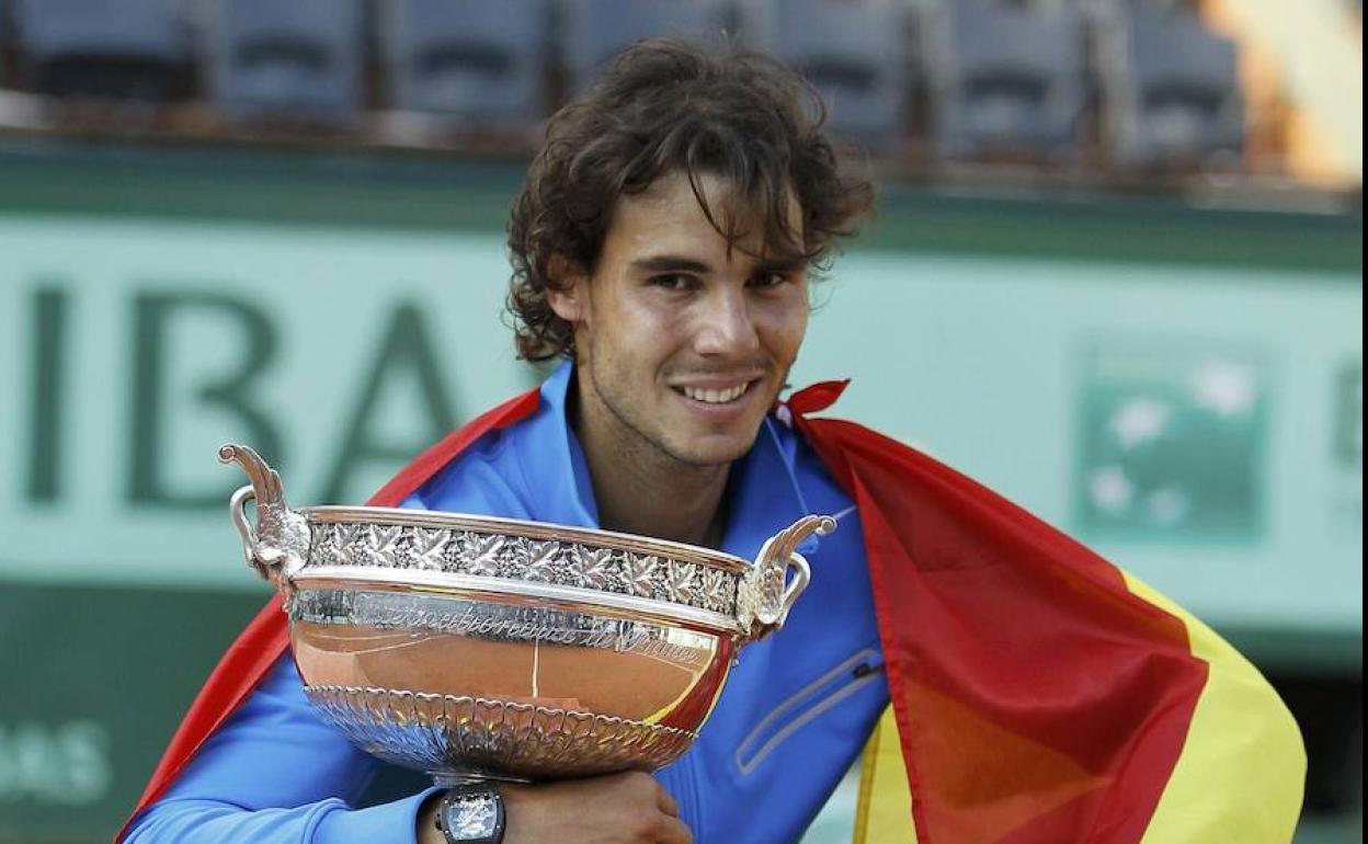 Nadal posa con el trofeo que le ganó a Federer en 2011 y la bandera española. 