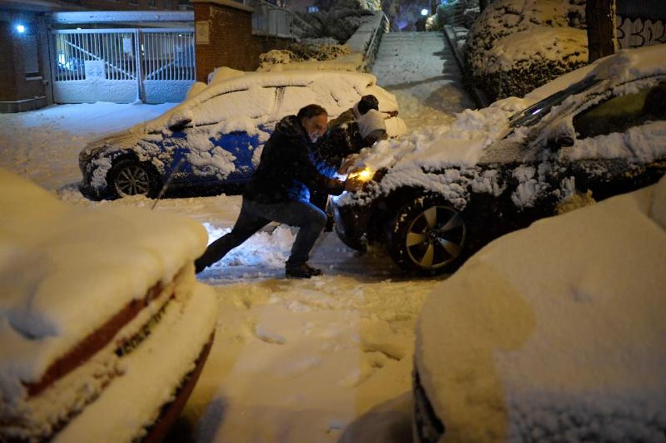 La gente empuja un coche atascado por la nieve en Madrid.