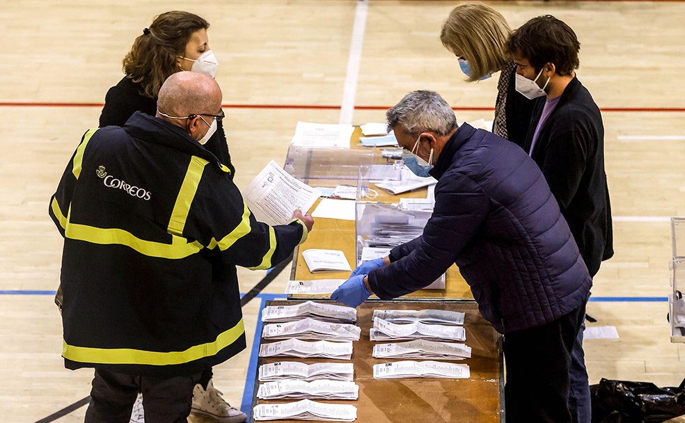 Varias personas vestidas con equipos de protección individual (EPI) realizan el recuento de votos en las mesas electorales.