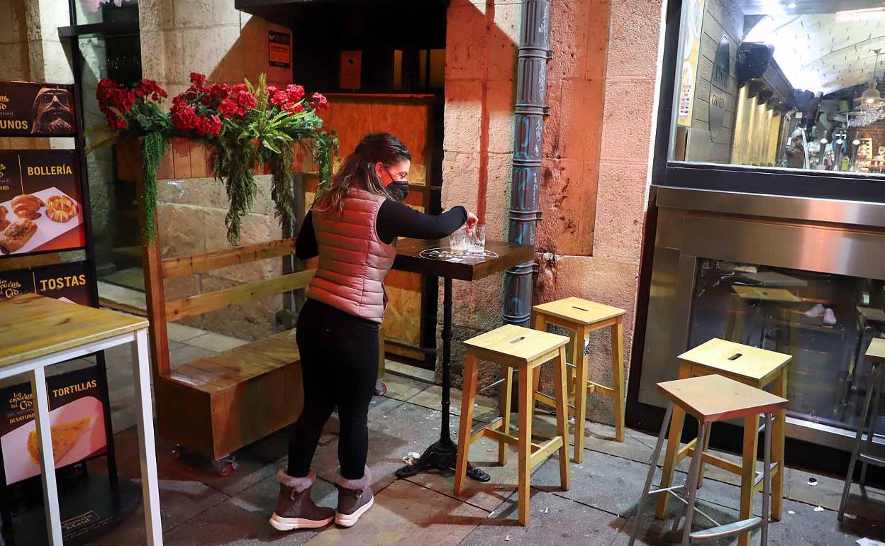 Una hostelera recoge la terraza para cumplir con el toque de queda en Burgos.