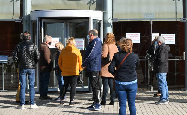 Gente que acudió al Centro Cultural Miguel Delibes para vacunarse, ante los carteles que anunciaban la suspensión. 