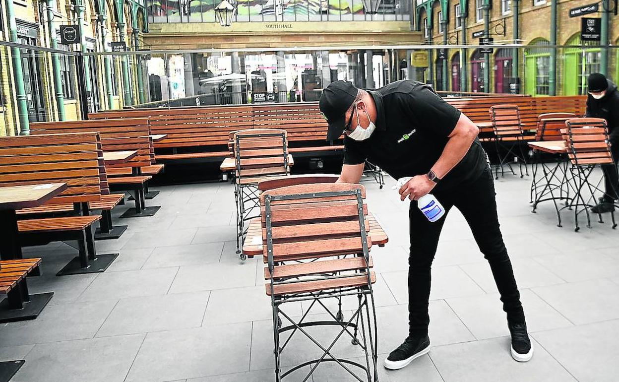 Un empleado limpia las mesas en un restaurante de Londres.