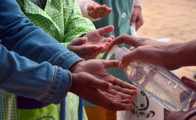 Maestras y profesores ayudan a los más pequeños a desinfectar sus manos.